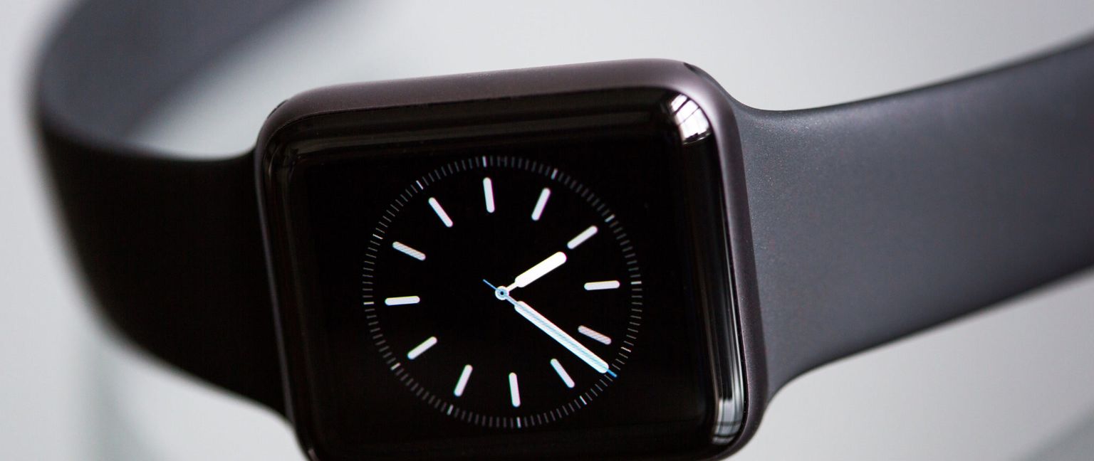 A close-up shot of a black Apple Watch displaying a clock face with white hour markers and hands.