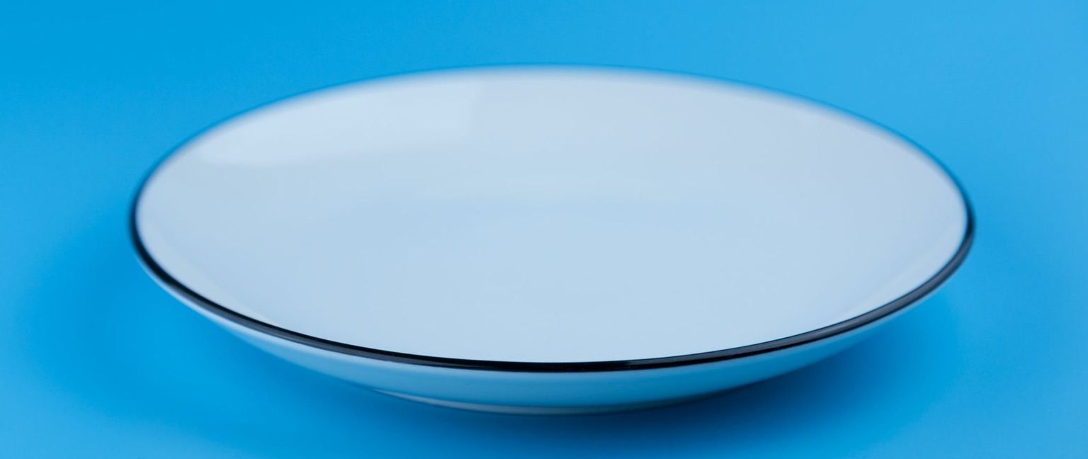 A white bowl with a black rim on a blue background.