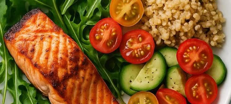 A vibrant plate featuring a grilled salmon fillet, fresh arugula, sliced cucumbers, halved cherry tomatoes, and a portion of bulgur or quinoa.