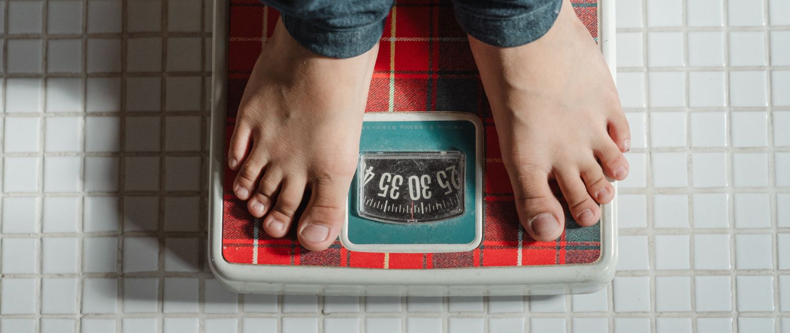 Person's bare feet standing on a plaid scale.