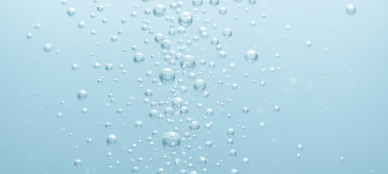 Close-up macro shot of tiny, shimmering bubbles ascending through clear water.