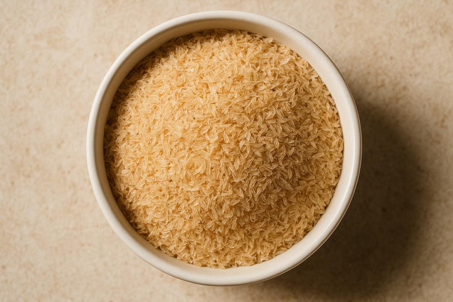 A beige bowl filled with light brown, flaky psyllium husks, the primary ingredient found in Metamucil, viewed from directly above.