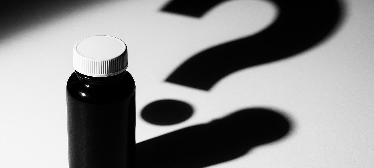 An unlabeled medicine bottle with a question mark shadow, symbolizing the unknowns and dangers of unapproved compounded drugs.