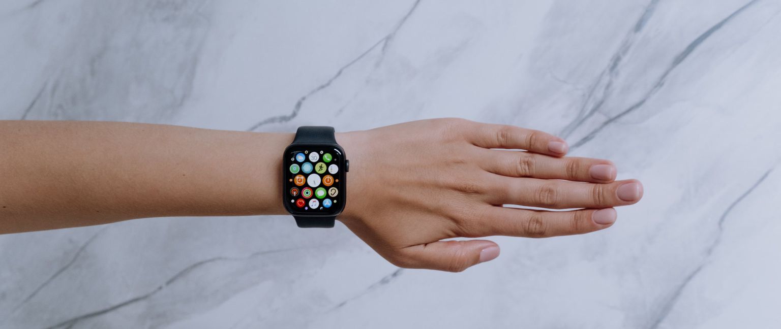 Close-up of a person's hand wearing an Apple Watch with the app menu displayed on the screen.