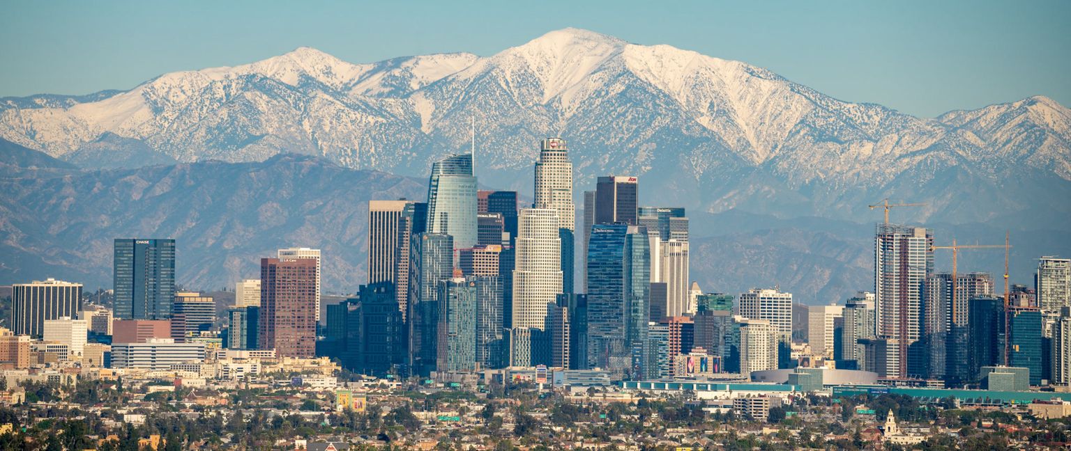 The downtown Los Angeles skyline with snow-capped mountains in the background.