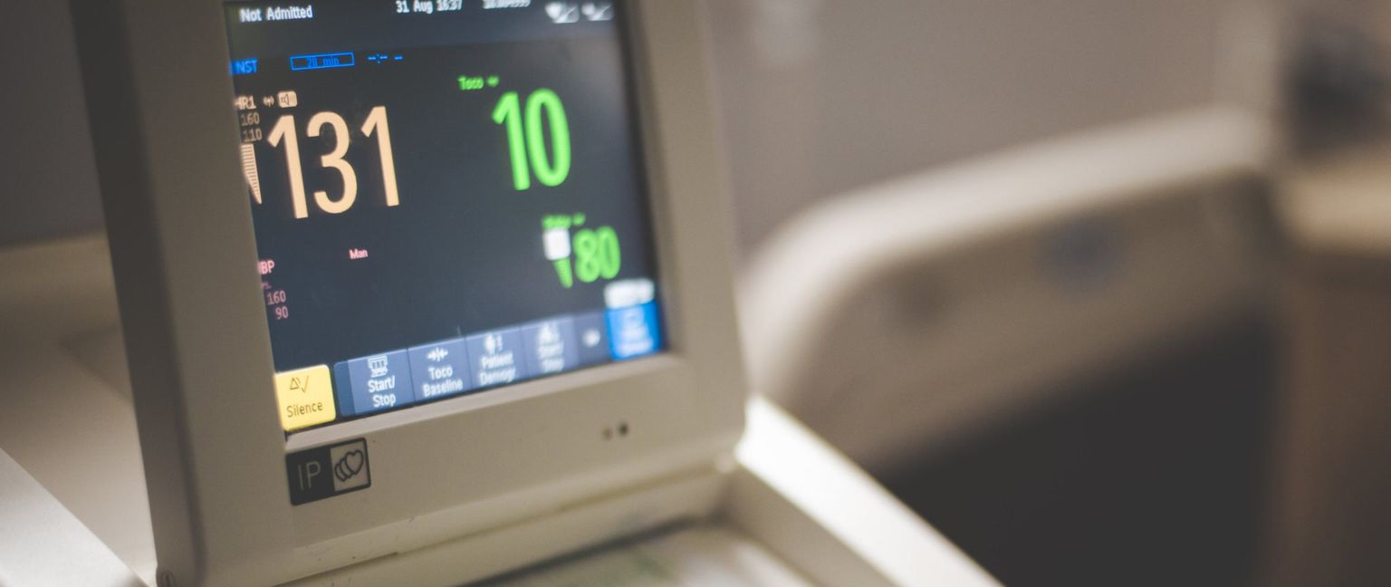 A close-up of a fetal monitor screen displaying heart rate, contractions, and blood pressure readings.